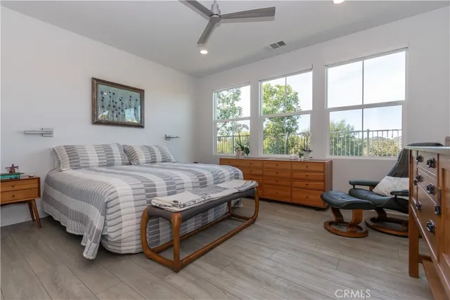 a bedroom with a bed wooden floor and a large window