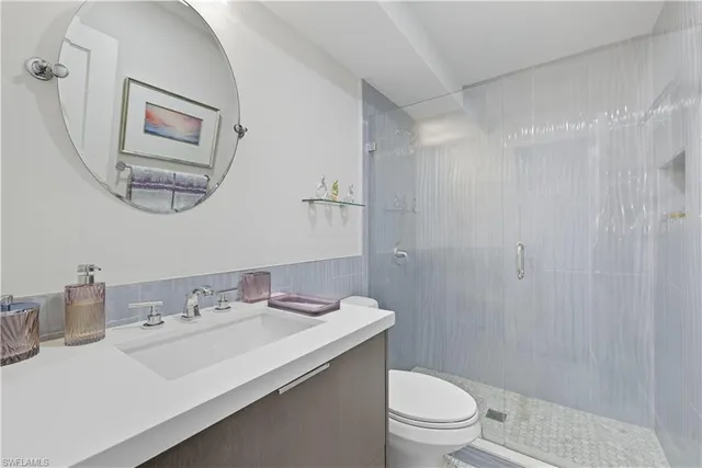 a bathroom with a sink a mirror a toilet and a shower