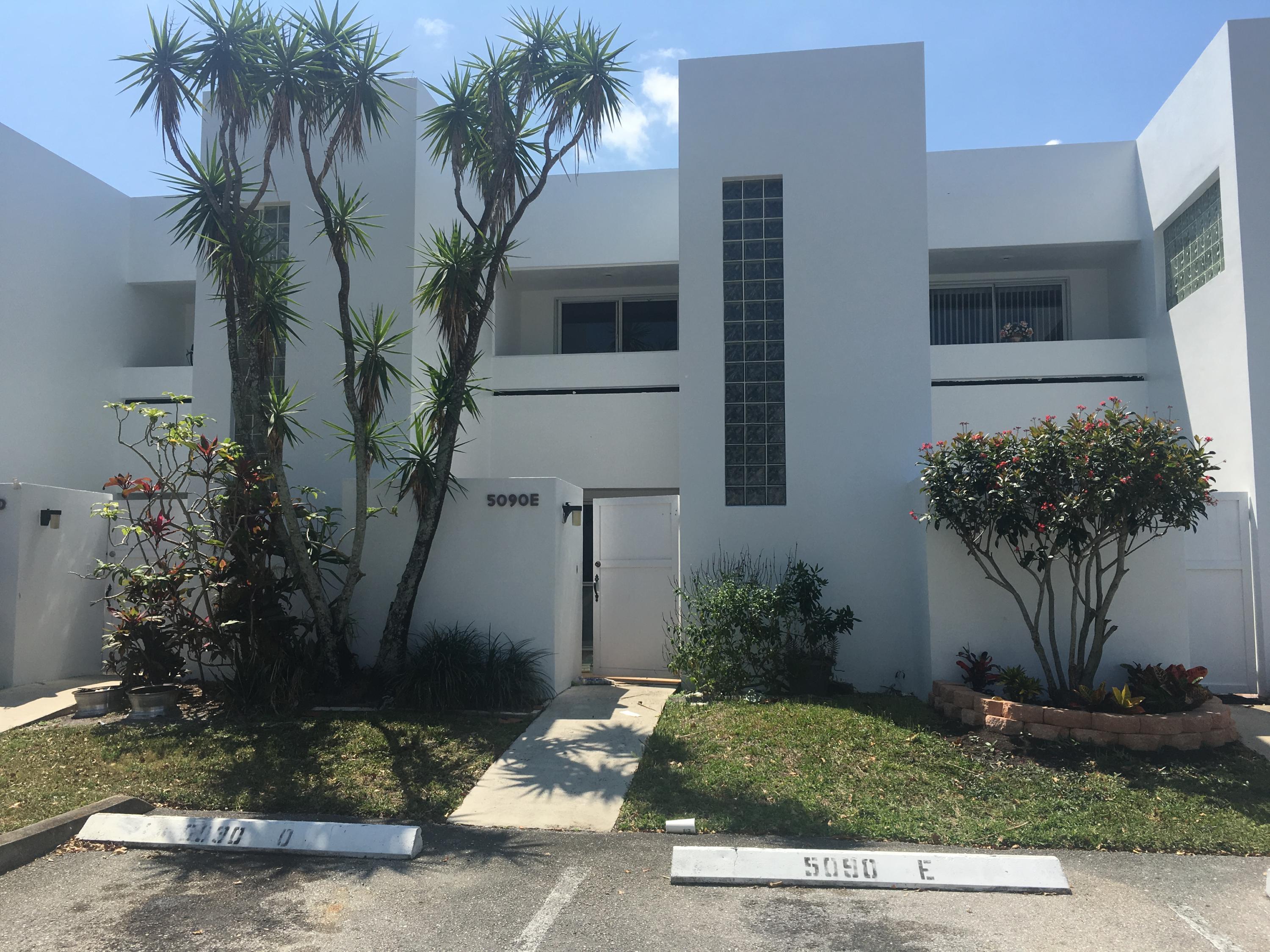 5090 Elmhurst Road, Unit E West Palm Beach, FL 33417 - Photo 1 of 12 a front view of a house with garden