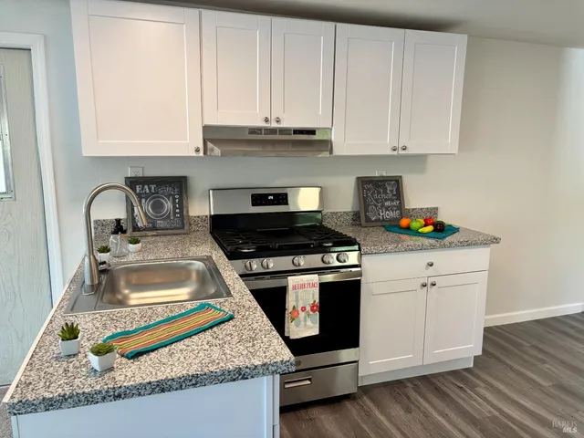 a kitchen with granite countertop a stove sink and cabinets