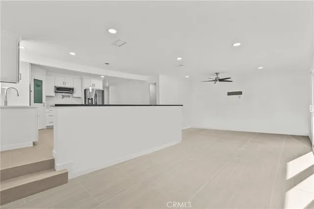 a view of kitchen with refrigerator and white cabinets