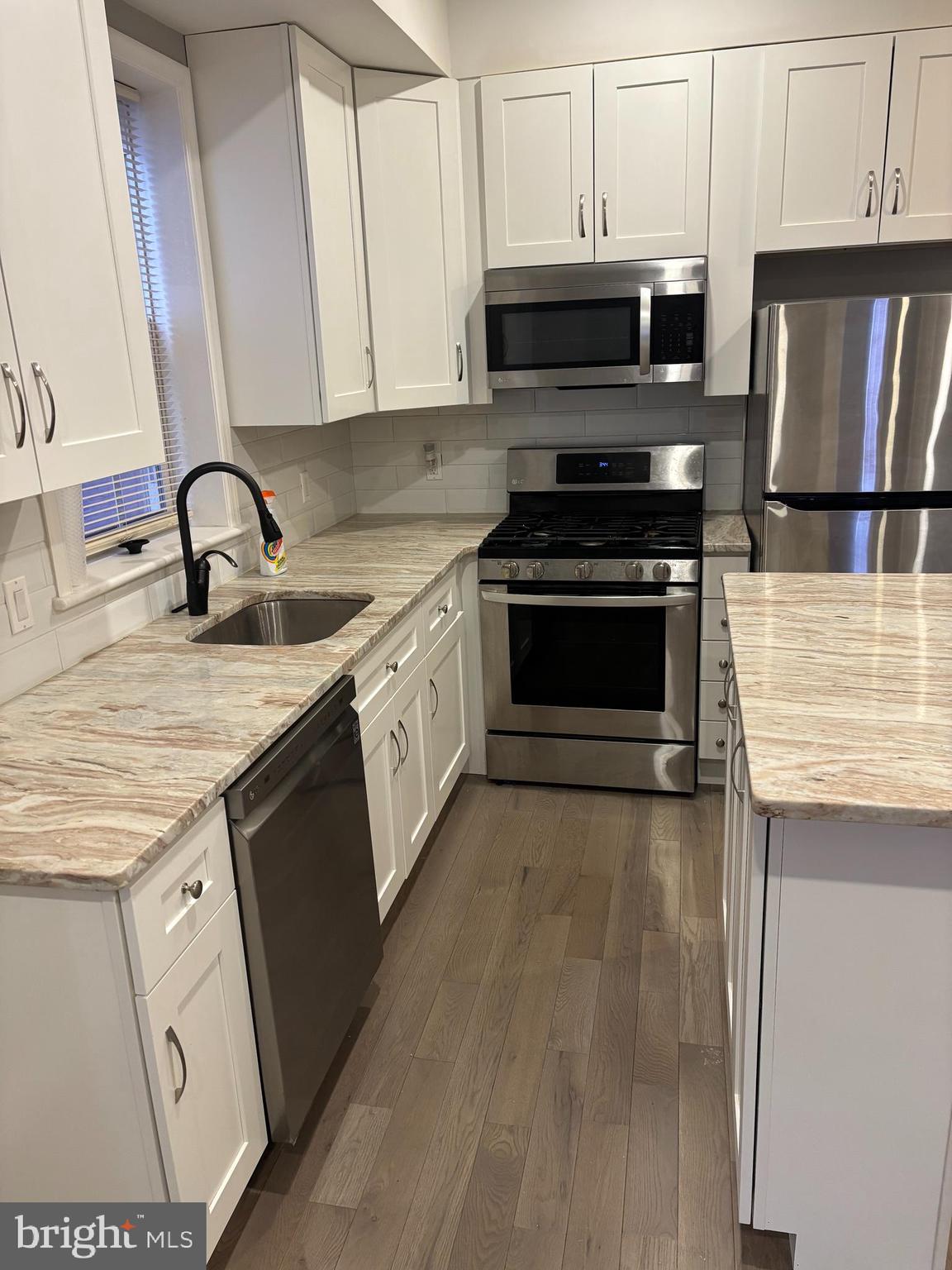 216 Buckingham Place, Unit 2 Philadelphia, PA 19104 - Photo 3 of 18 a kitchen with granite countertop a stove top oven a sink and a microwave