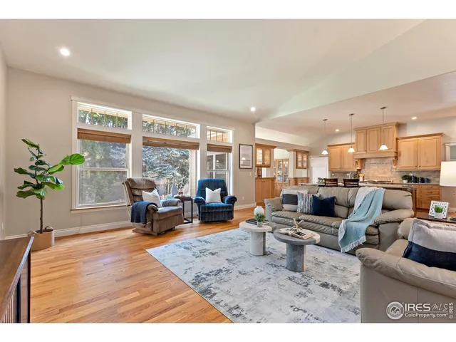 a living room with furniture large window and wooden floor
