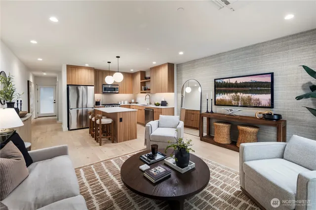 a living room with furniture kitchen view and a wooden floor
