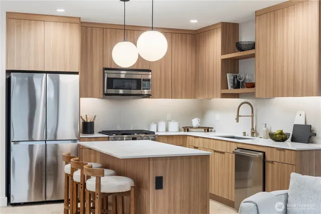 a kitchen with stainless steel appliances granite countertop a sink a microwave a refrigerator and a stove