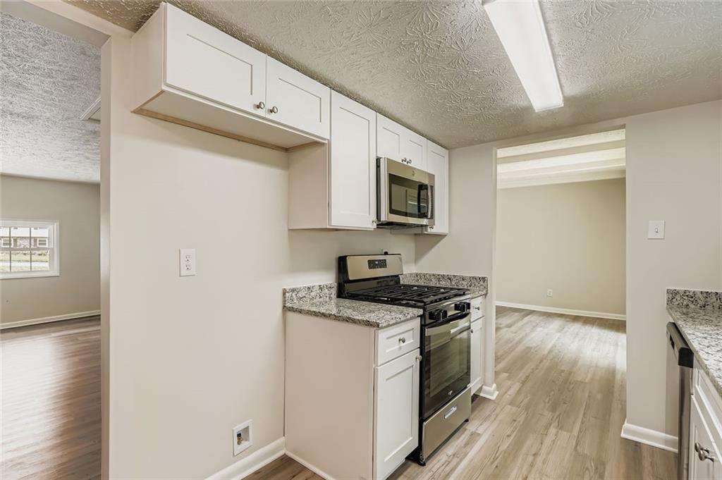 6678 Collier Way Riverdale, GA 30296 - Photo 11 of 29 a kitchen with granite countertop a stove top oven a sink a counter space and cabinets