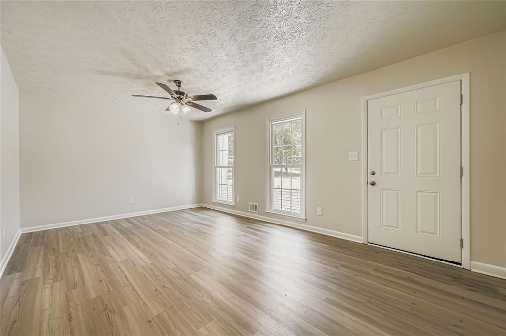 6678 Collier Way Riverdale, GA 30296 - Photo 6 of 29 an empty room with wooden floor fan and windows