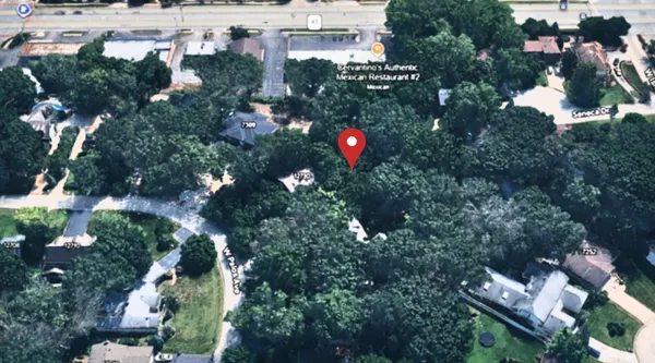 an aerial view of residential houses with outdoor space and trees