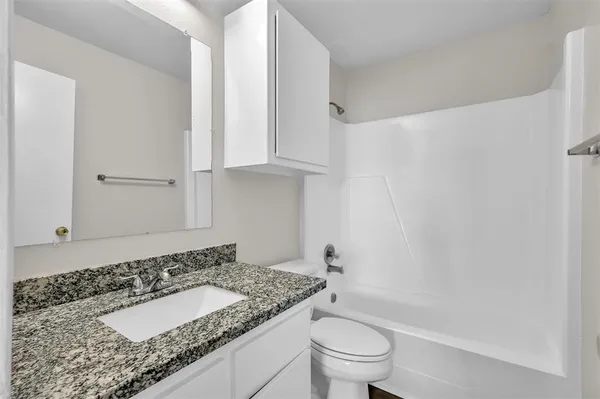 a bathroom with a granite countertop sink a toilet and bathtub