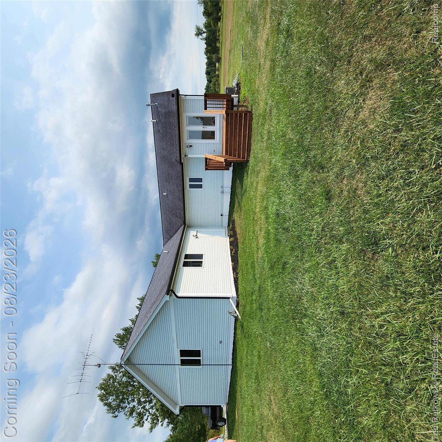 12350 Masters Road Memphis, MI 48041 - Photo 9 of 45 White siding exterior with a dark shingle roof, featuring a wooden deck with railing and double glass doors
