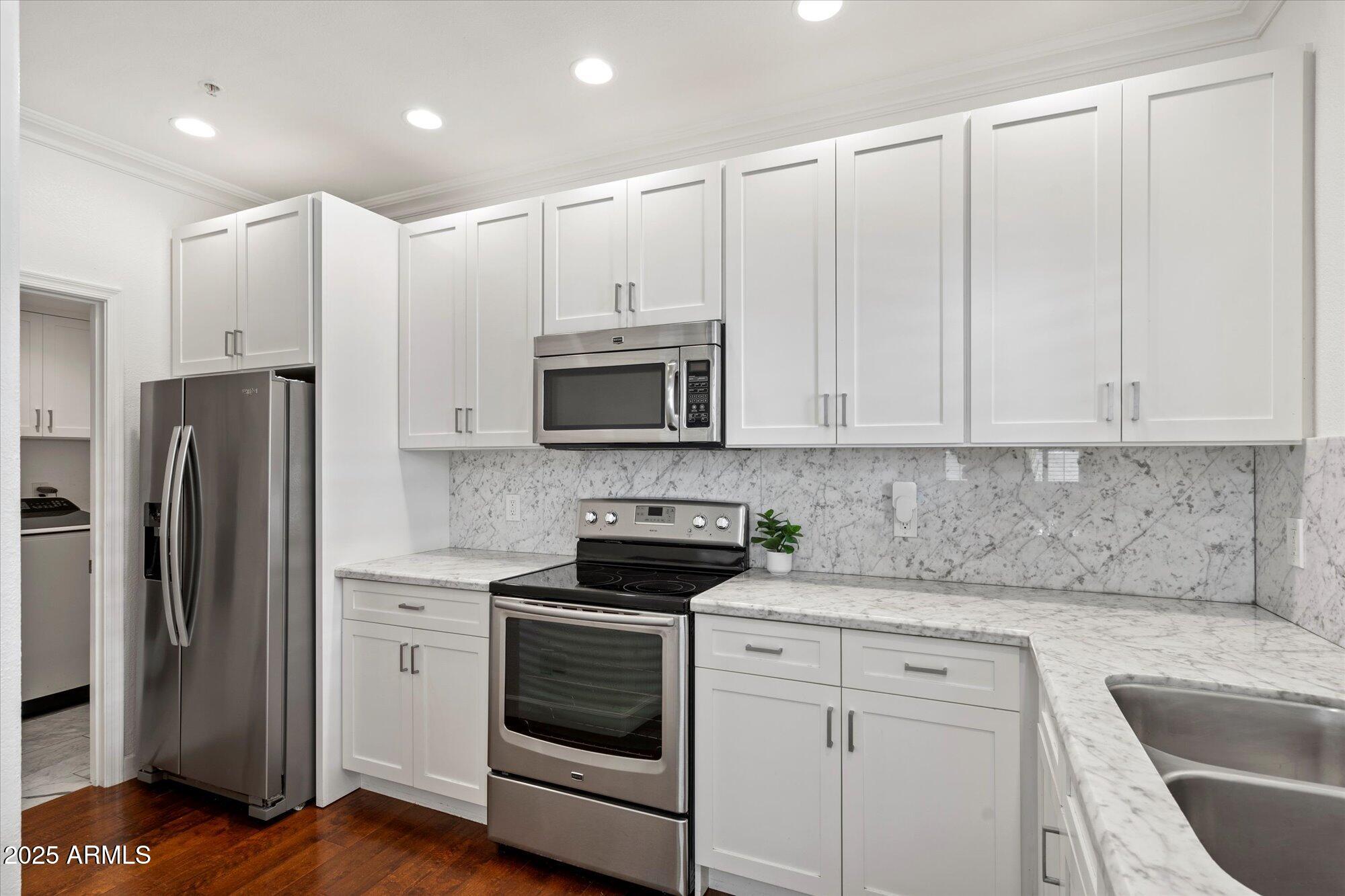 7710 East Gainey Ranch Road, Unit 139 Scottsdale, AZ 85258 - Photo 16 of 38 a kitchen with stainless steel appliances granite countertop white cabinets a refrigerator and a sink