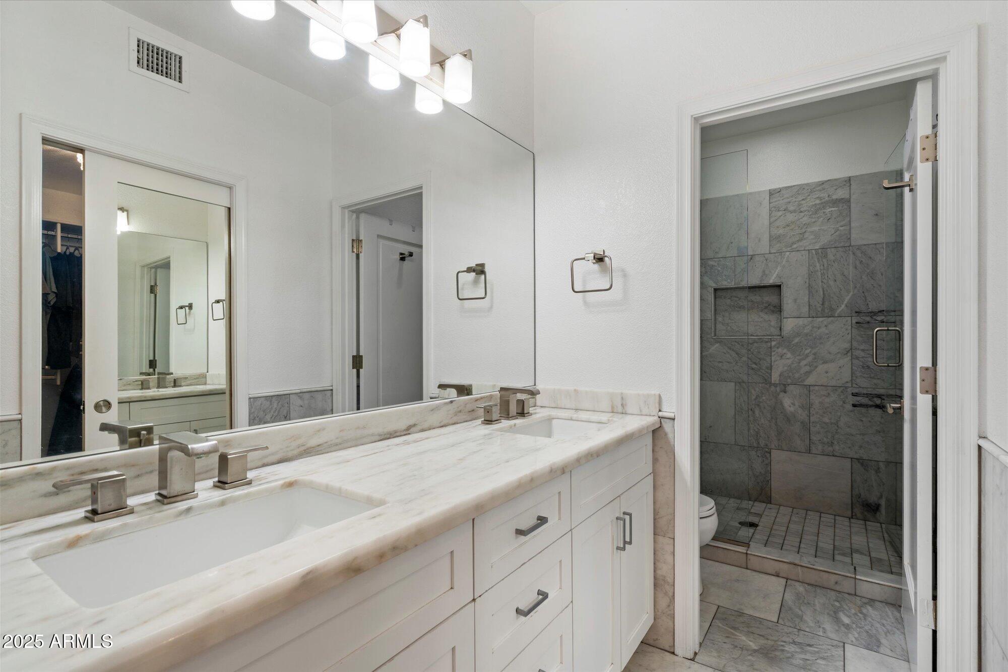 7710 East Gainey Ranch Road, Unit 139 Scottsdale, AZ 85258 - Photo 21 of 38 a bathroom with a granite countertop sink a mirror and a shower