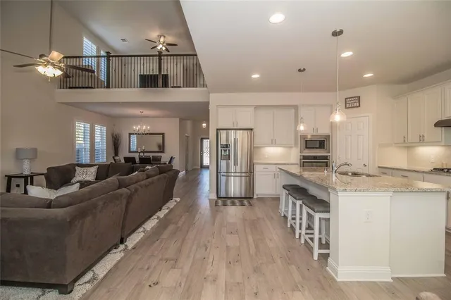 a living room with stainless steel appliances kitchen island granite countertop furniture wooden floor and a kitchen view