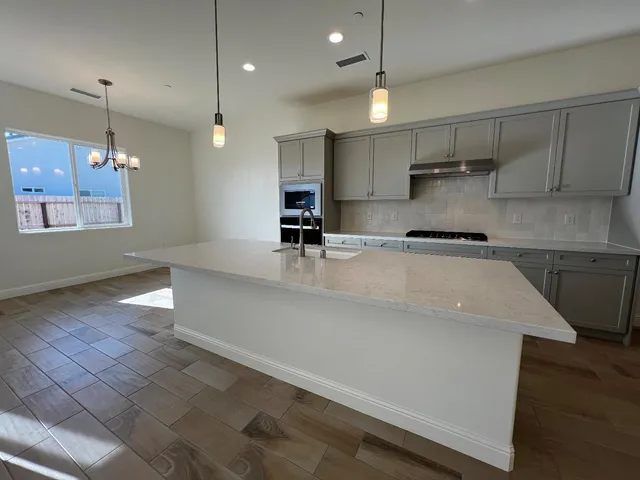 a kitchen with stainless steel appliances granite countertop a sink a stove and a wooden floors