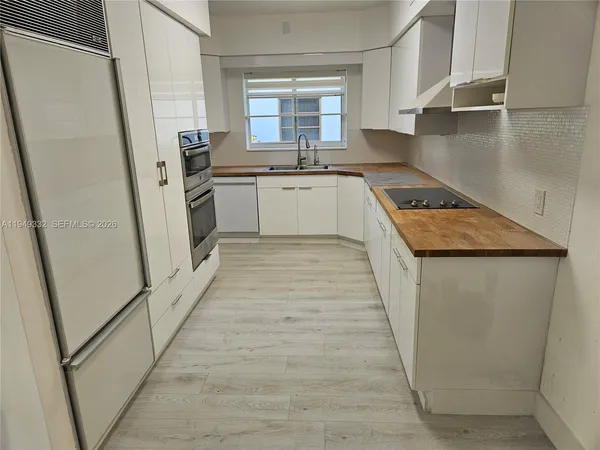 a kitchen with a sink a refrigerator a stove and white cabinets