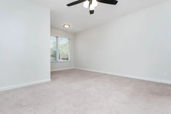 an empty room with a chandelier fan and windows