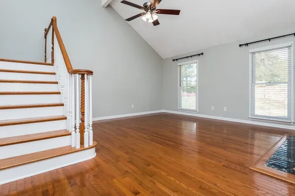 a view of an empty room with wooden floor and a window