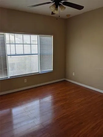 a view of an empty room with wooden floor and a window