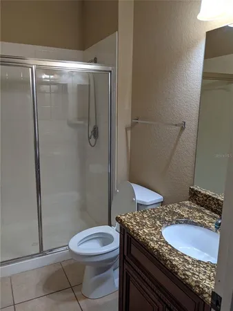 a bathroom with a granite countertop sink toilet and shower