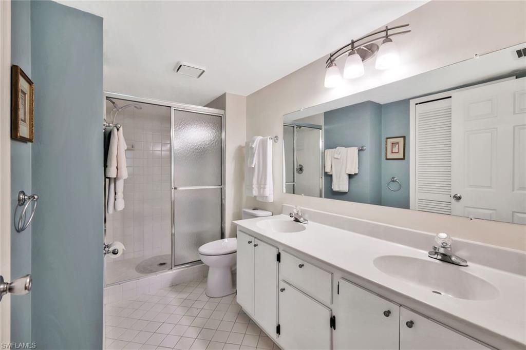 234 Pebble Beach Boulevard, Unit 306 Naples, FL 34113 - Photo 15 of 19 a bathroom with a double vanity sink mirror double and shower