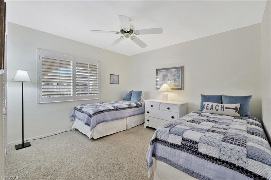 234 Pebble Beach Boulevard, Unit 306 Naples, FL 34113 - Photo 18 of 19 a spacious bedroom with a bed and a chandelier
