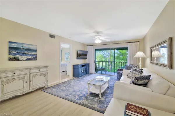 a living room with furniture a flat screen tv and a large window