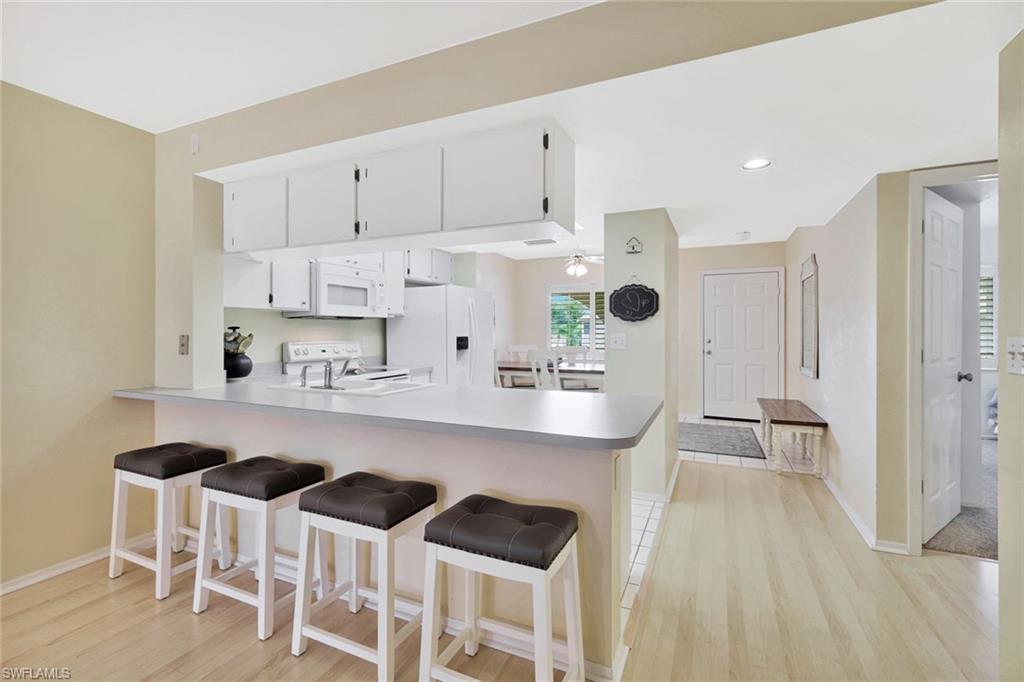 234 Pebble Beach Boulevard, Unit 306 Naples, FL 34113 - Photo 9 of 19 a kitchen with stainless steel appliances kitchen island granite countertop a table chairs and a refrigerator