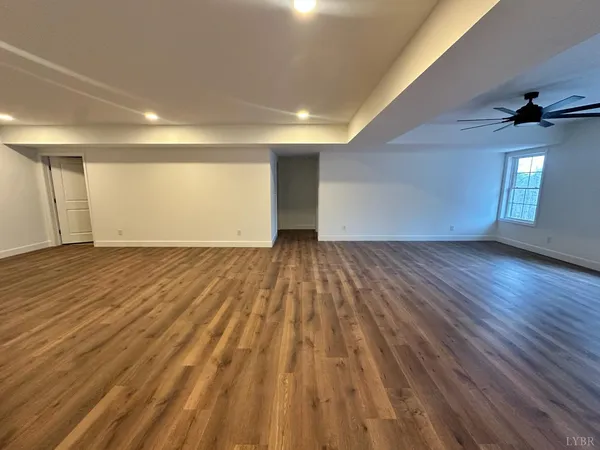 an empty room with wooden floor ceiling fan and windows