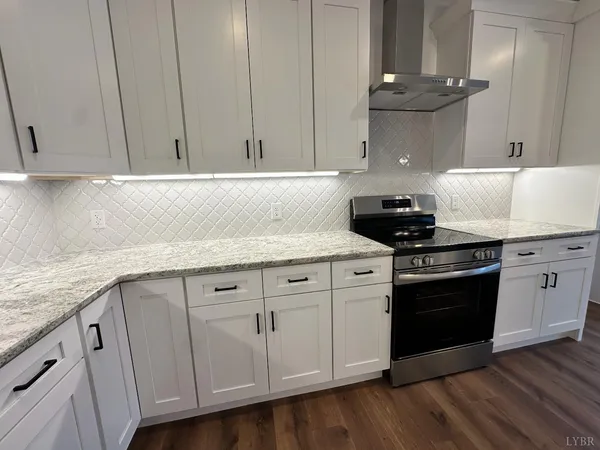 a kitchen with granite countertop white cabinets and a stove