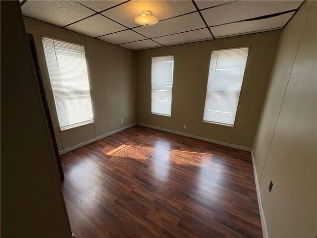 an empty room with wooden floor and windows
