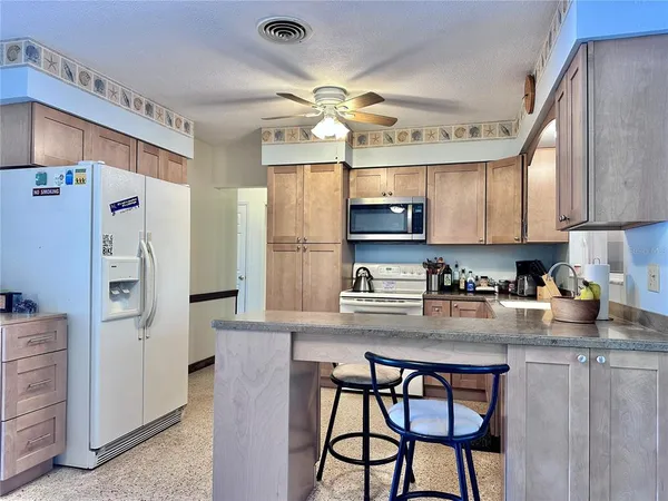a kitchen with stainless steel appliances granite countertop a refrigerator a sink dishwasher a dining table and chairs with wooden floor