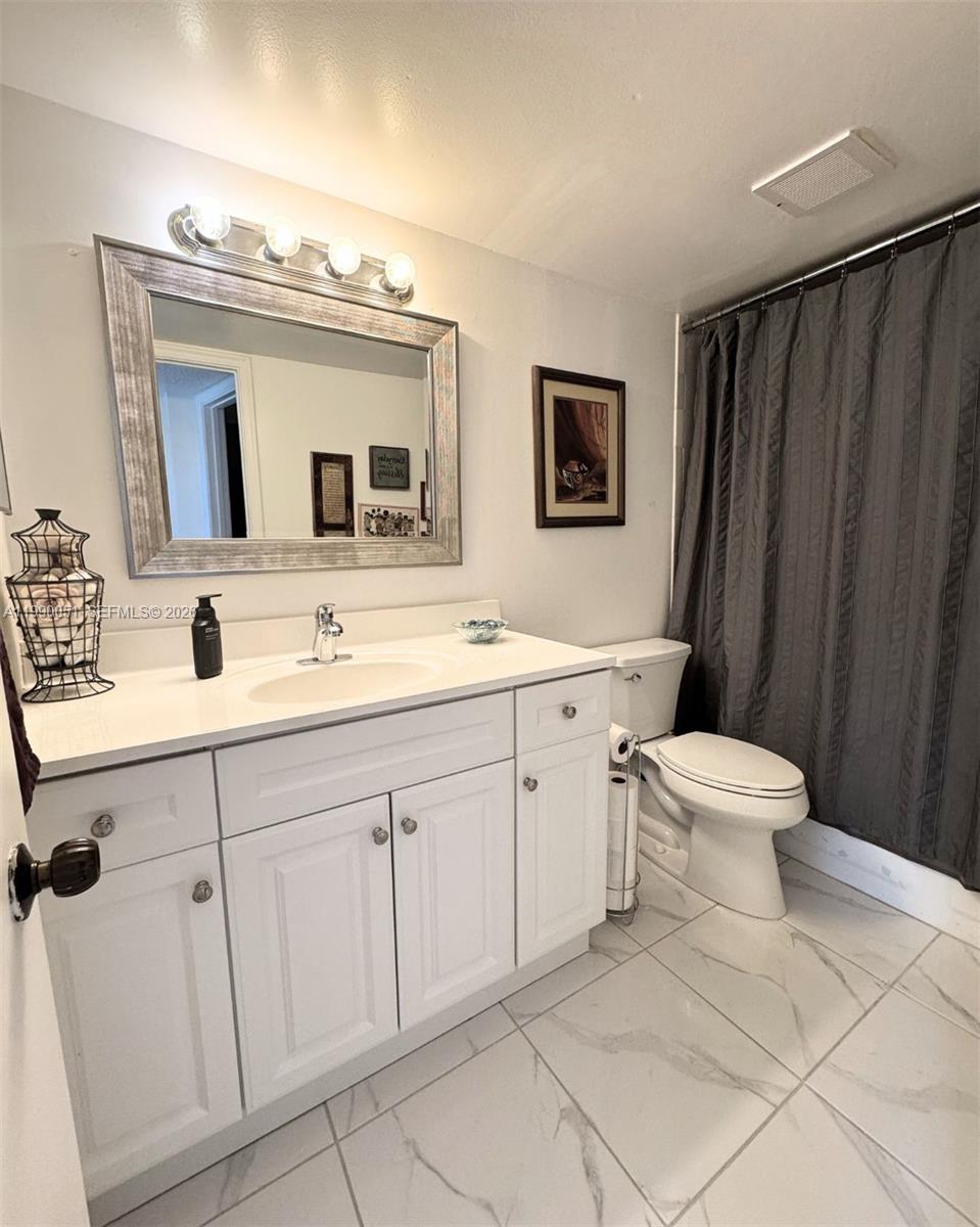 3776 Inverrary Boulevard, Unit 301R Lauderhill, FL 33319 - Photo 12 of 31 a bathroom with a double vanity sink mirror and toilet