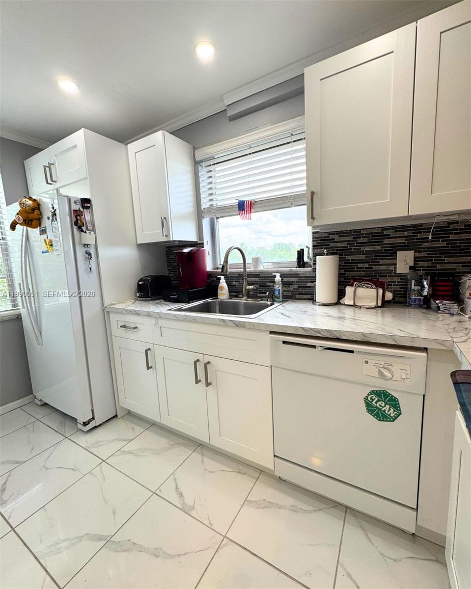 3776 Inverrary Boulevard, Unit 301R Lauderhill, FL 33319 - Photo 31 of 31 a kitchen with a sink a refrigerator and cabinets
