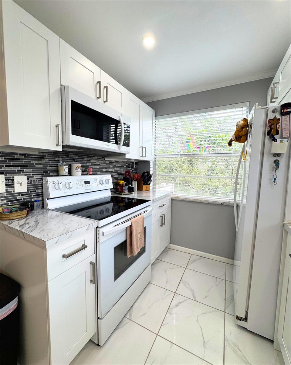 3776 Inverrary Boulevard, Unit 301R Lauderhill, FL 33319 - Photo 6 of 31 a kitchen with stainless steel appliances granite countertop a stove a sink and a microwave