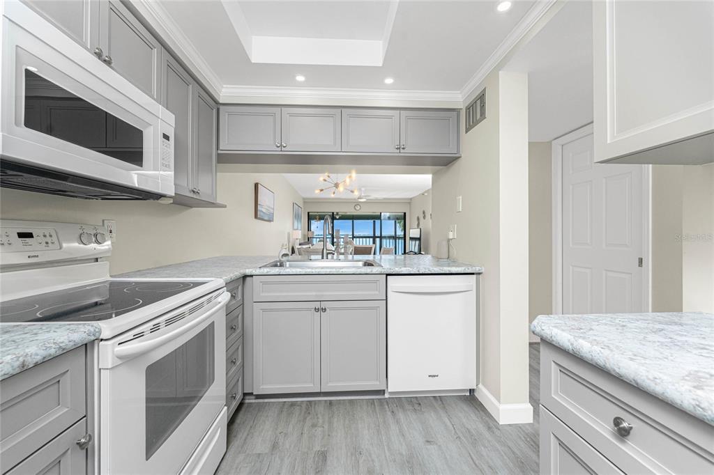 1551 Beach Road, Unit 306 Englewood, FL 34223 - Photo 5 of 50 a kitchen with stainless steel appliances granite countertop a sink and cabinets with wooden floor