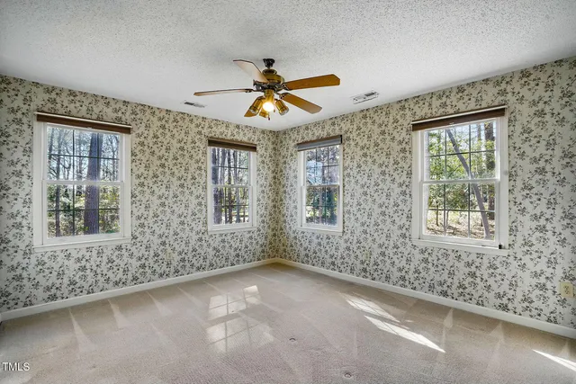 an empty room with windows and fan