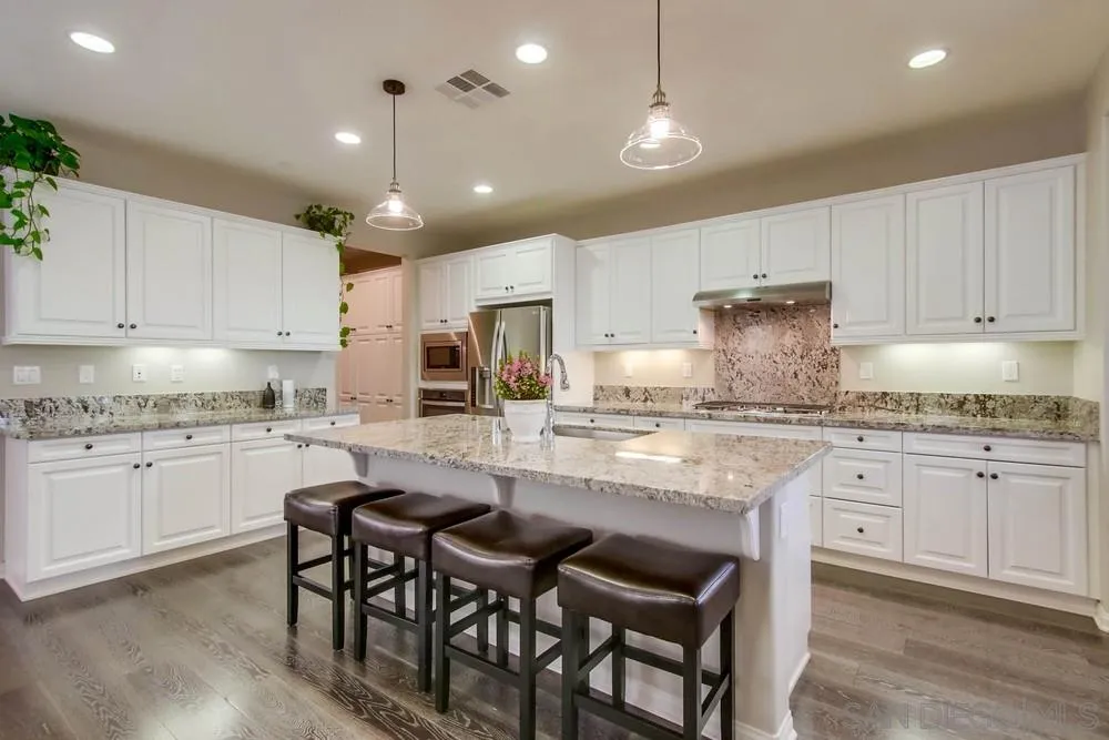 15712 Potomac Ridge Road San Diego, CA 92127 - Photo 4 of 17 a kitchen with granite countertop white cabinets and chairs
