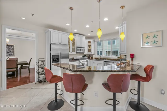 a kitchen with kitchen island granite countertop a stove a chandelier a dining table and chairs