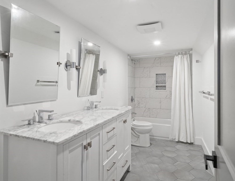 161 Lowell Street, Unit 1 Somerville, MA 02143 - Photo 13 of 18 a bathroom with a double vanity sink a toilet and a large mirror