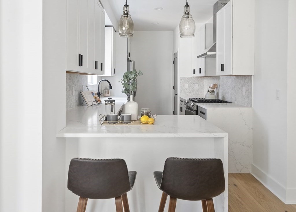 161 Lowell Street, Unit 1 Somerville, MA 02143 - Photo 6 of 18 a kitchen with stainless steel appliances a white table chairs and a refrigerator