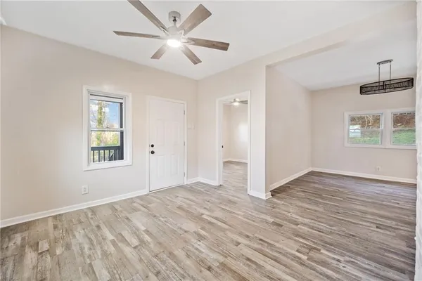 a view of an empty room with a window and wooden floor