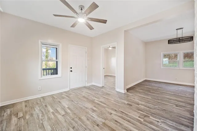 a view of an empty room with a window and wooden floor