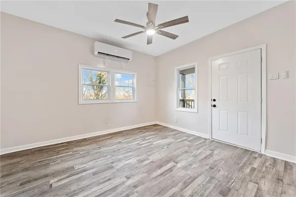 a view of an empty room with wooden floor and a window