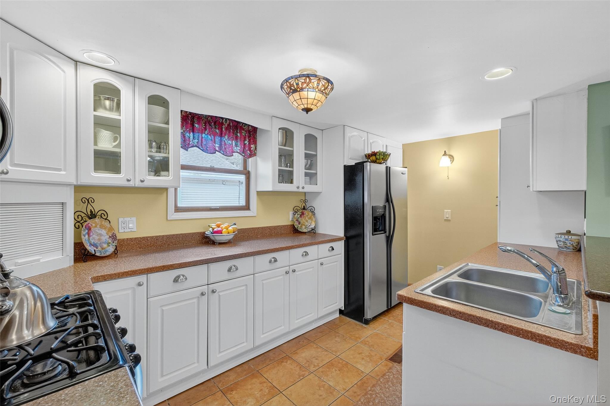 333 Canoe Hill Road Saugerties, NY 12477 - Photo 14 of 34 Kitchen with white cabinetry, stainless steel fridge with ice dispenser, glass insert cabinets, black gas range oven, and light tile patterned floors