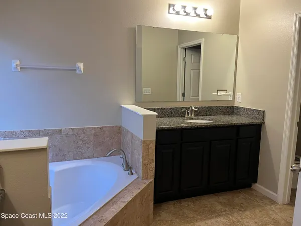a bathroom with a granite countertop shower sink and mirror