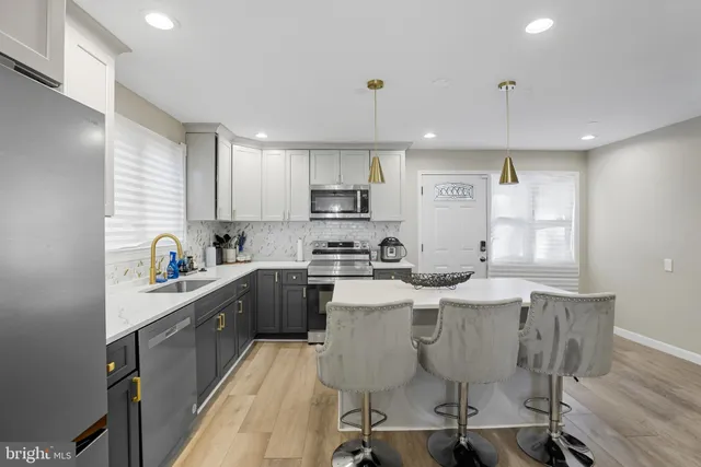 a kitchen with stainless steel appliances granite countertop a sink a stove a refrigerator cabinets a dining table and chairs