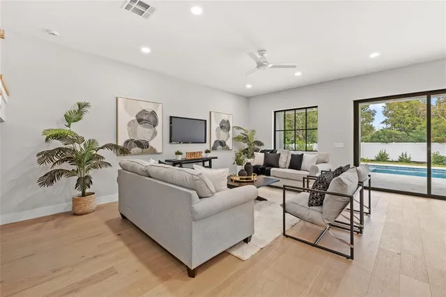an empty room with wooden floor chandelier and windows