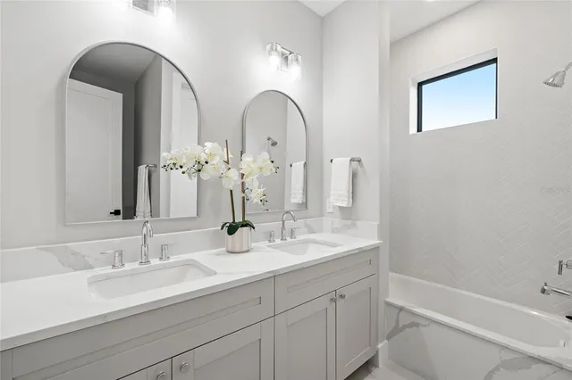 a bathroom with a double vanity sink a mirror a bathtub and shower