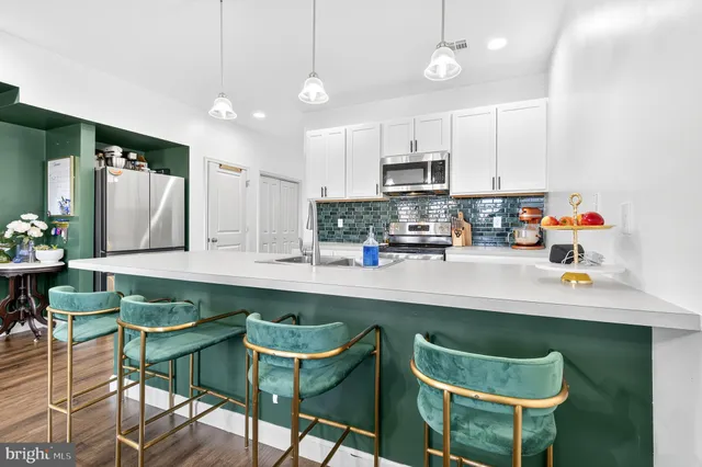 a kitchen with stainless steel appliances a dining table chairs and microwave