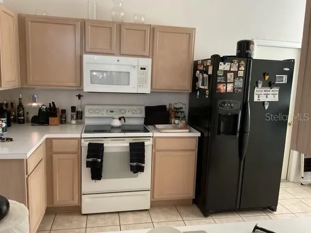 a view of a kitchen with fridge and wooden floor